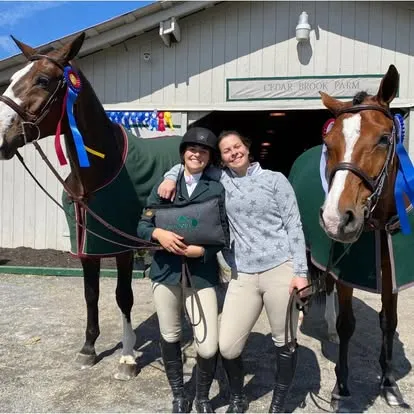 Two riders and two horses outside Cedar Brook Farm barn