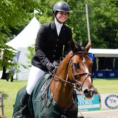 Smiling rider on bay horse in outdoor show ring